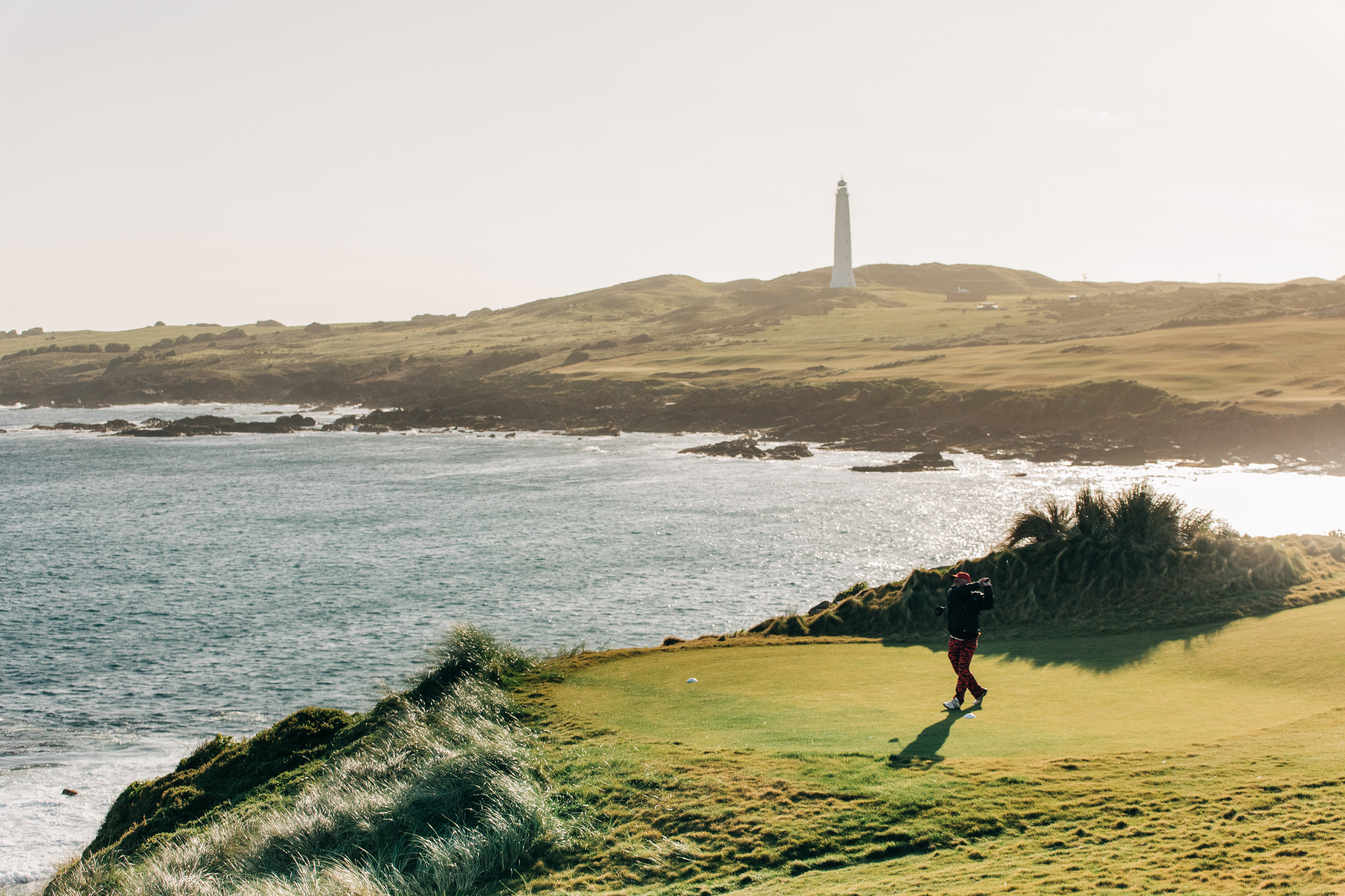 Landscape with a golfer taking a swing at Cape Wickham Golf Course.