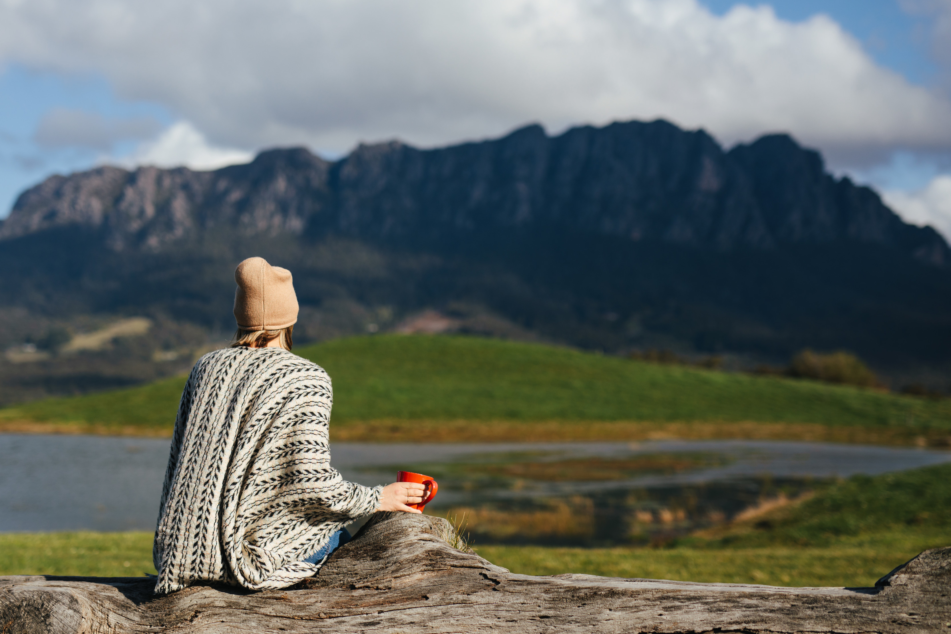 Person outside, sitting down, looking out to the incredible scenery, while enjoying a cup of coffee at the Eagles Nest Retreat.