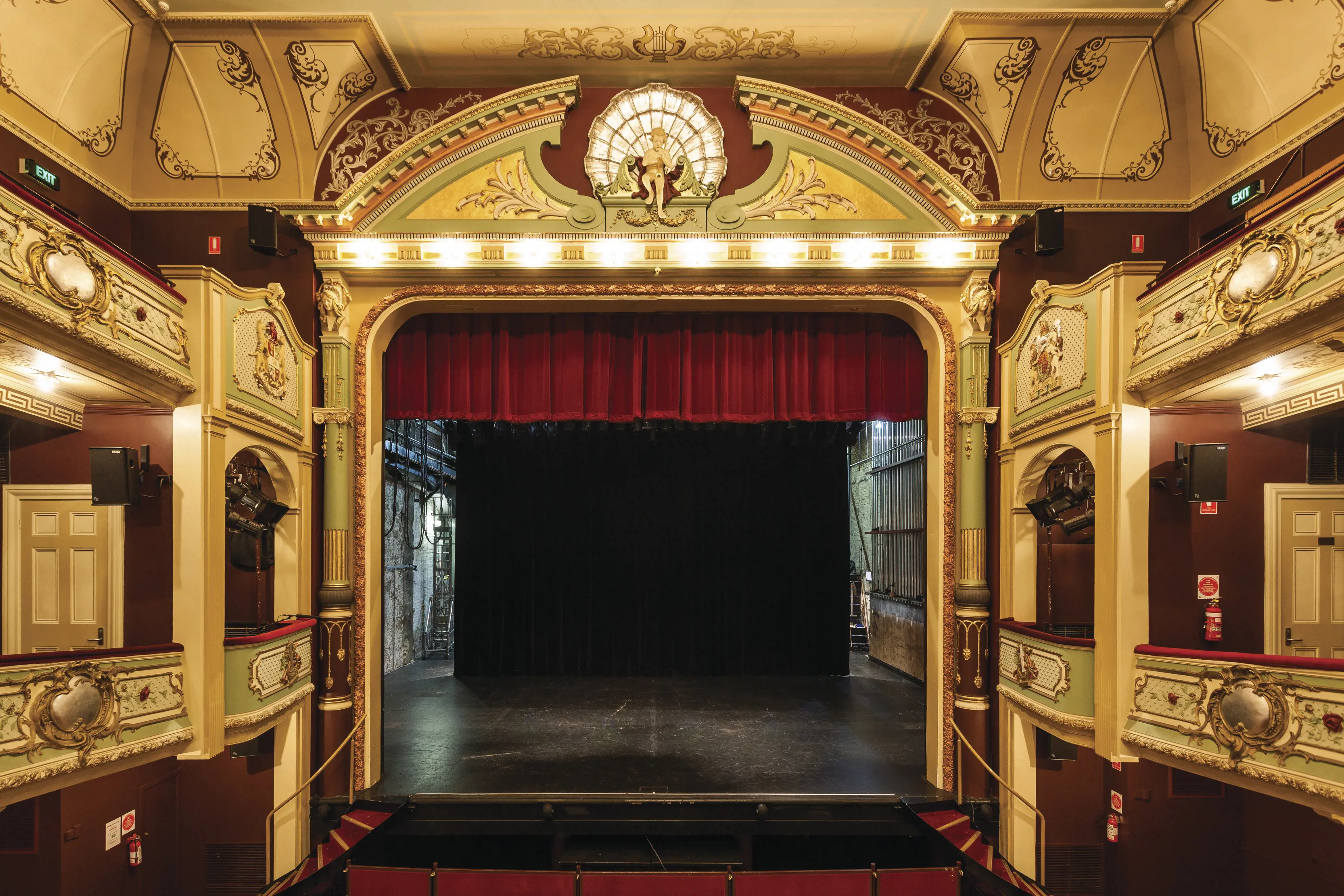 A stage with red velvet curtains and ornate decorations.