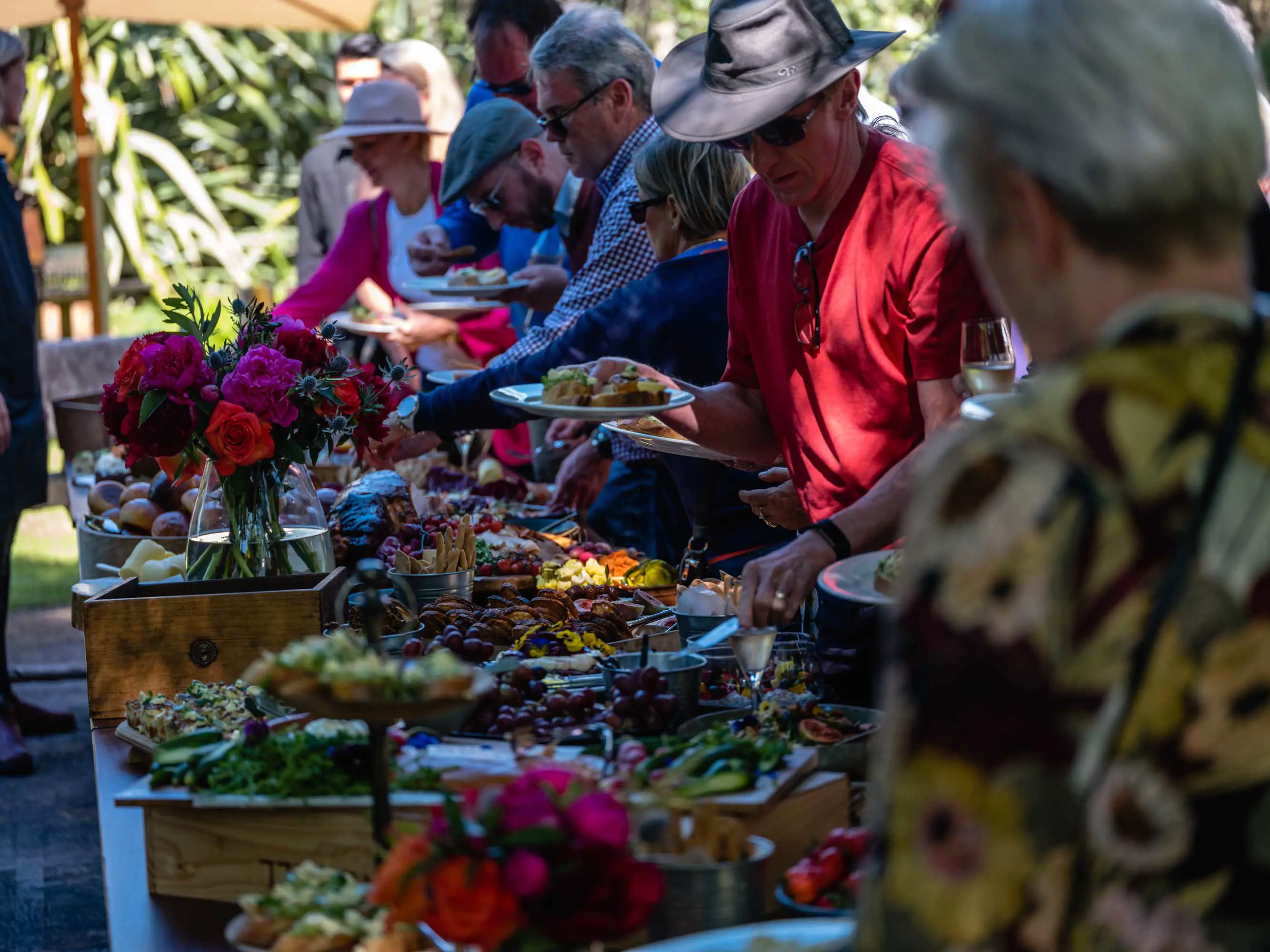 A long table with large platters of freshly cooked vegetables, breads, cheese and meats.