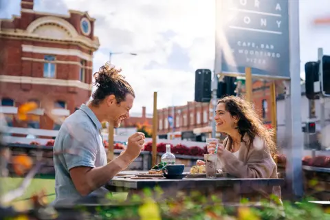 A couple enjoy food and coffee sat outside at Room for a Pony cafe and bar in Hobart.