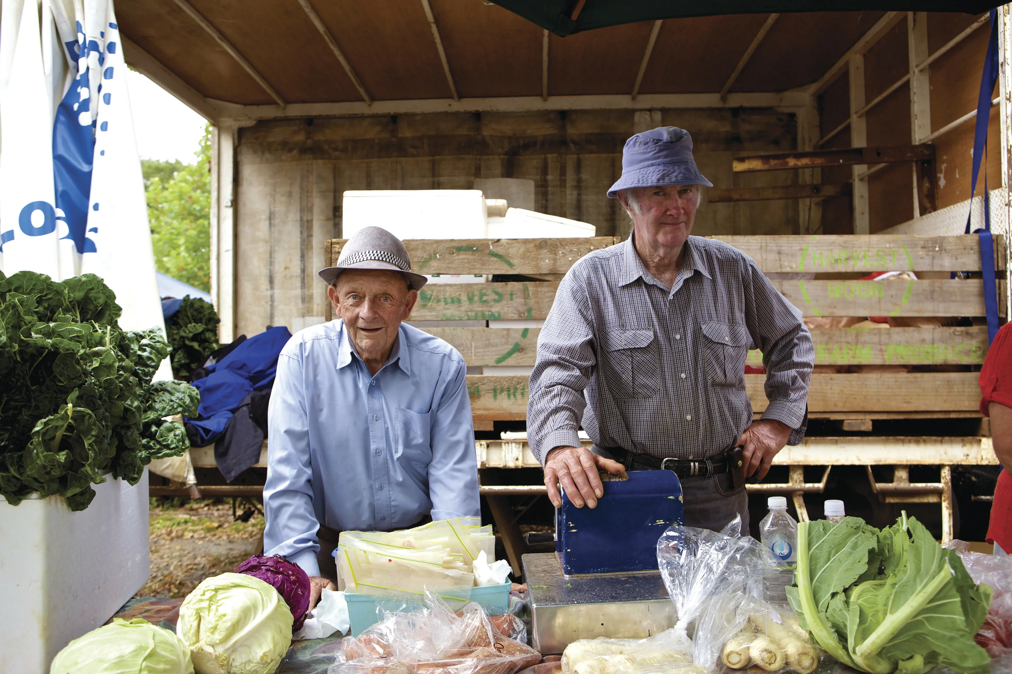 Two friendly local men standing in front of a stall with produce at Evandale market.
