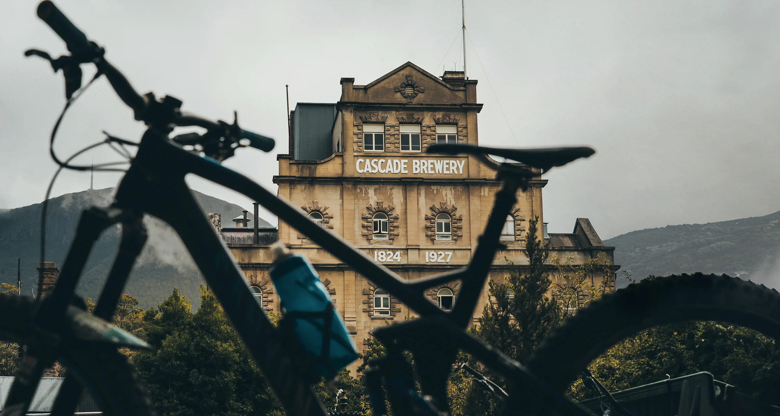 A mountain bike in the foreground of a photograph of the façade of the Cascade Brewery.