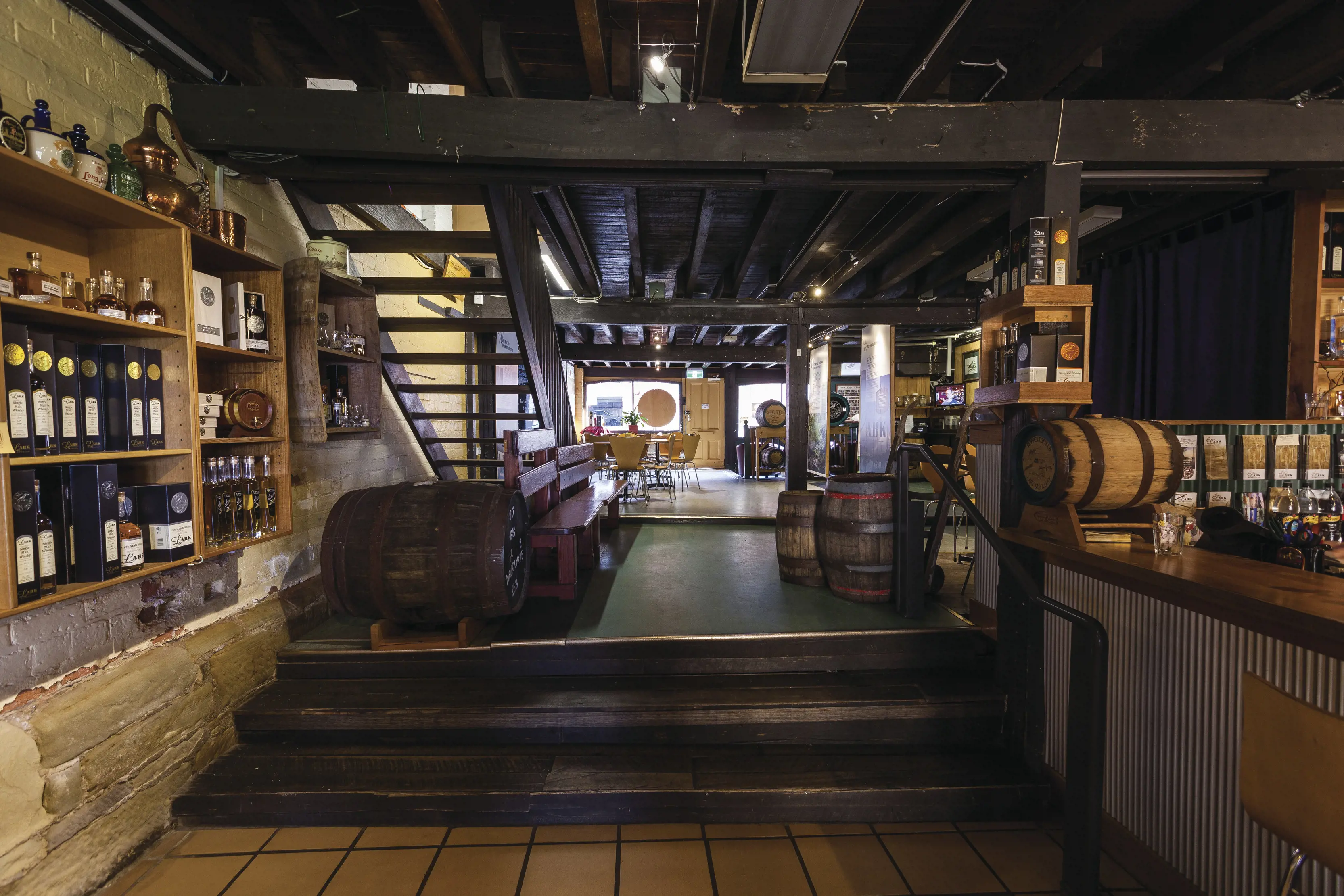 inside the charming and rustic Lark Distillery, surrounded by wooden interior and large barrels.
