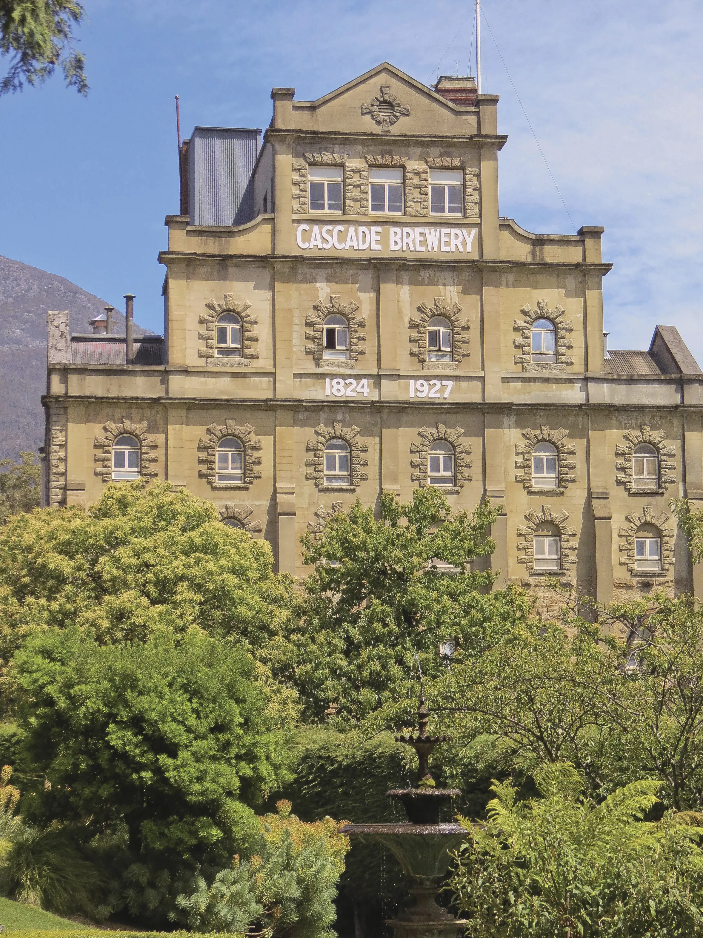 The stunning exterior of the Cascade Brewery, Hobart, Tasmania, is Australia's oldest brewery. Lush green gardens fill the foreground. 