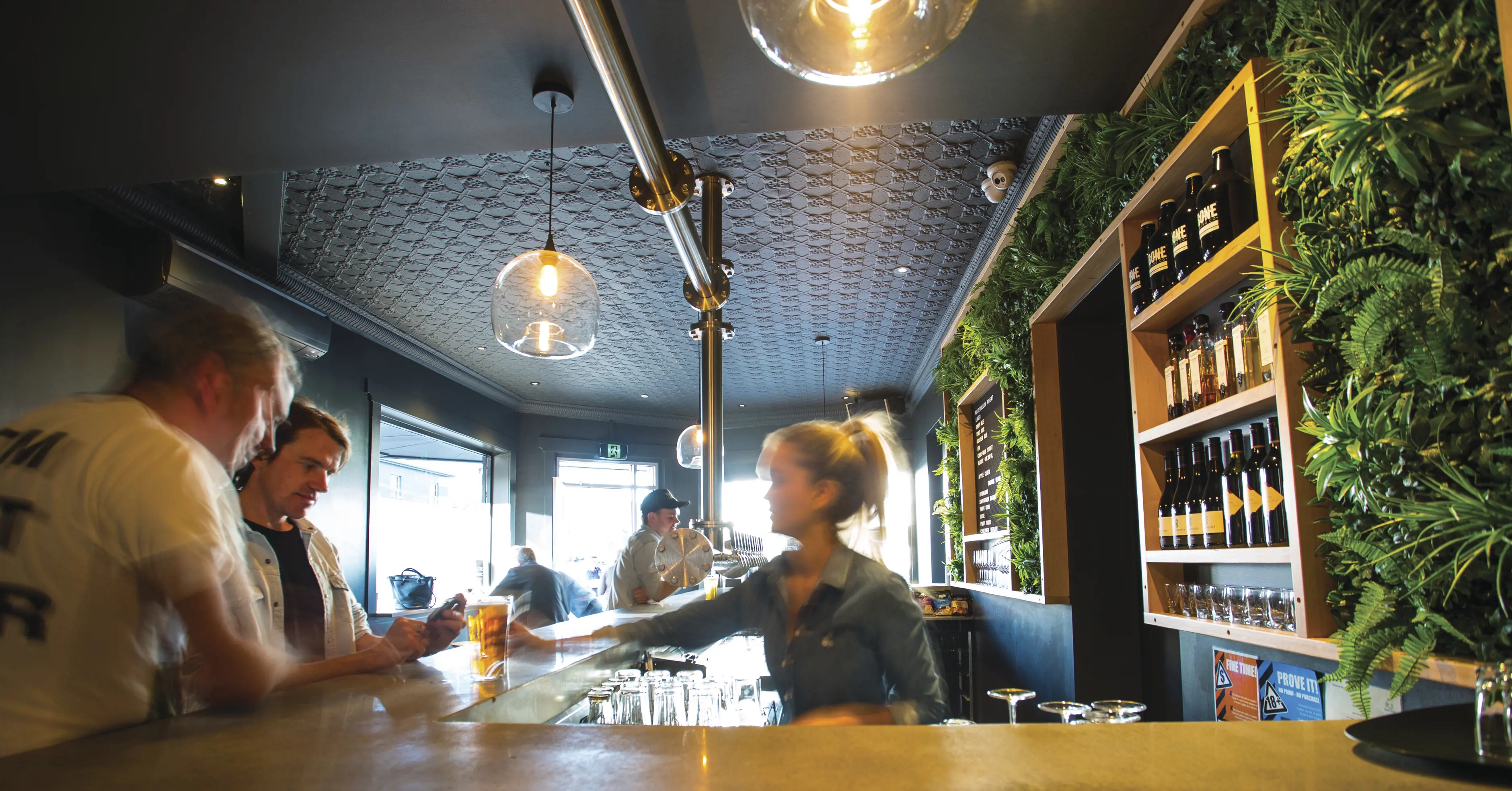 Image inside the T-Bone Brewing Co. of a busy scene with a woman serving to guys beer. 