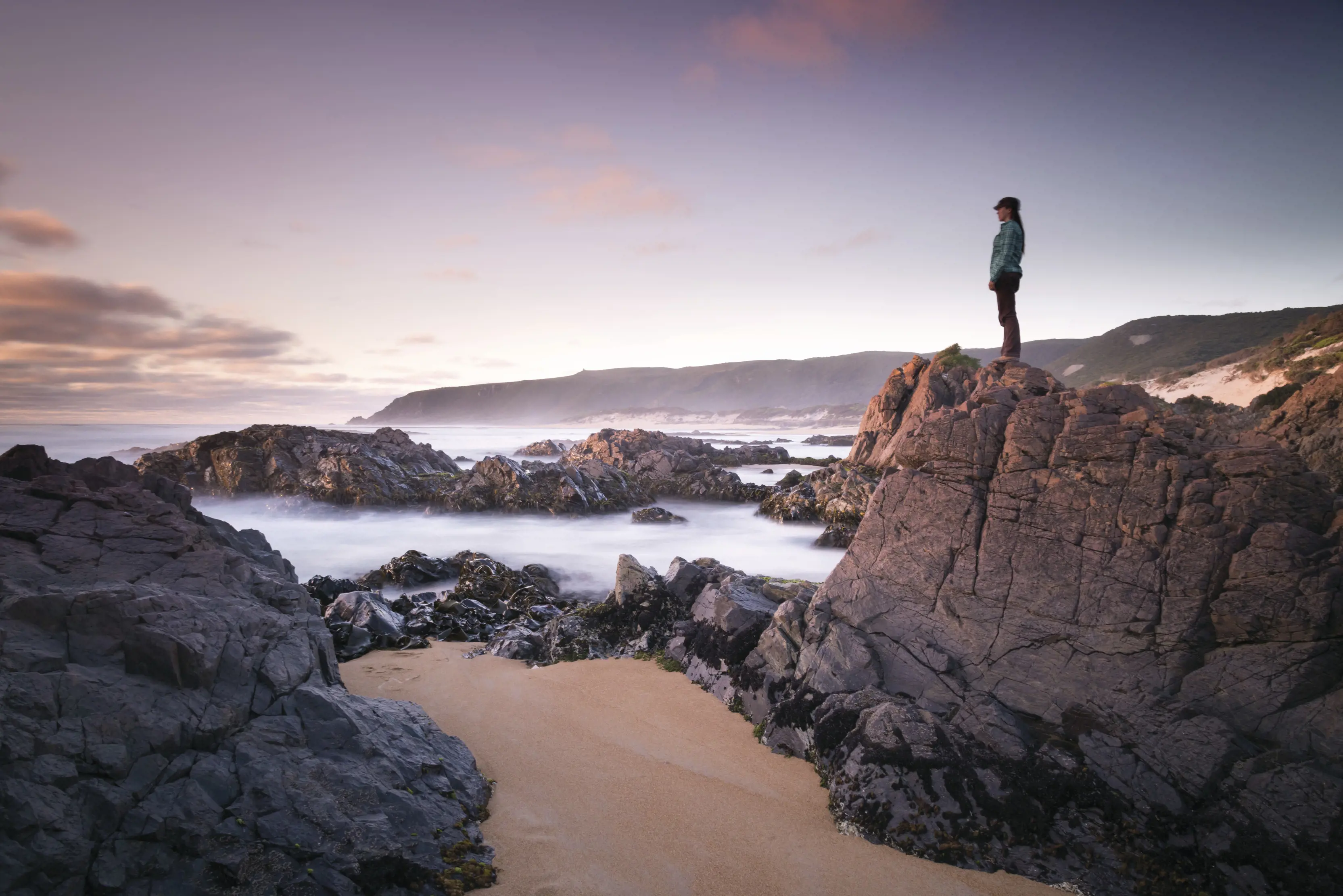 Spectacular landscape image of a person standing on a rock, overlooking the picturesque Trial Harbour, located in the northern part of Ocean Beach.