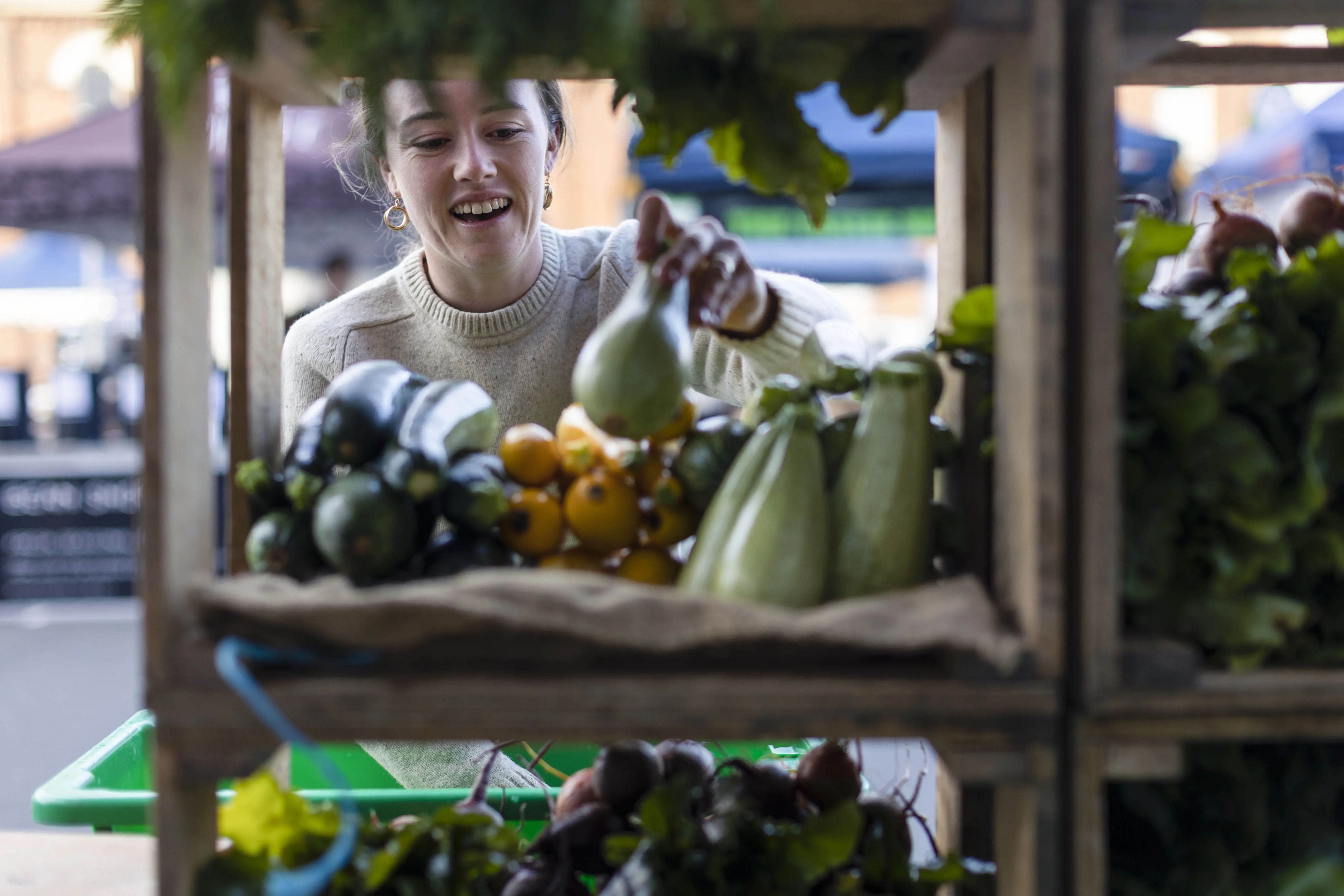 A young woman buying fresh vegetables from a stall at the Harvest Maket