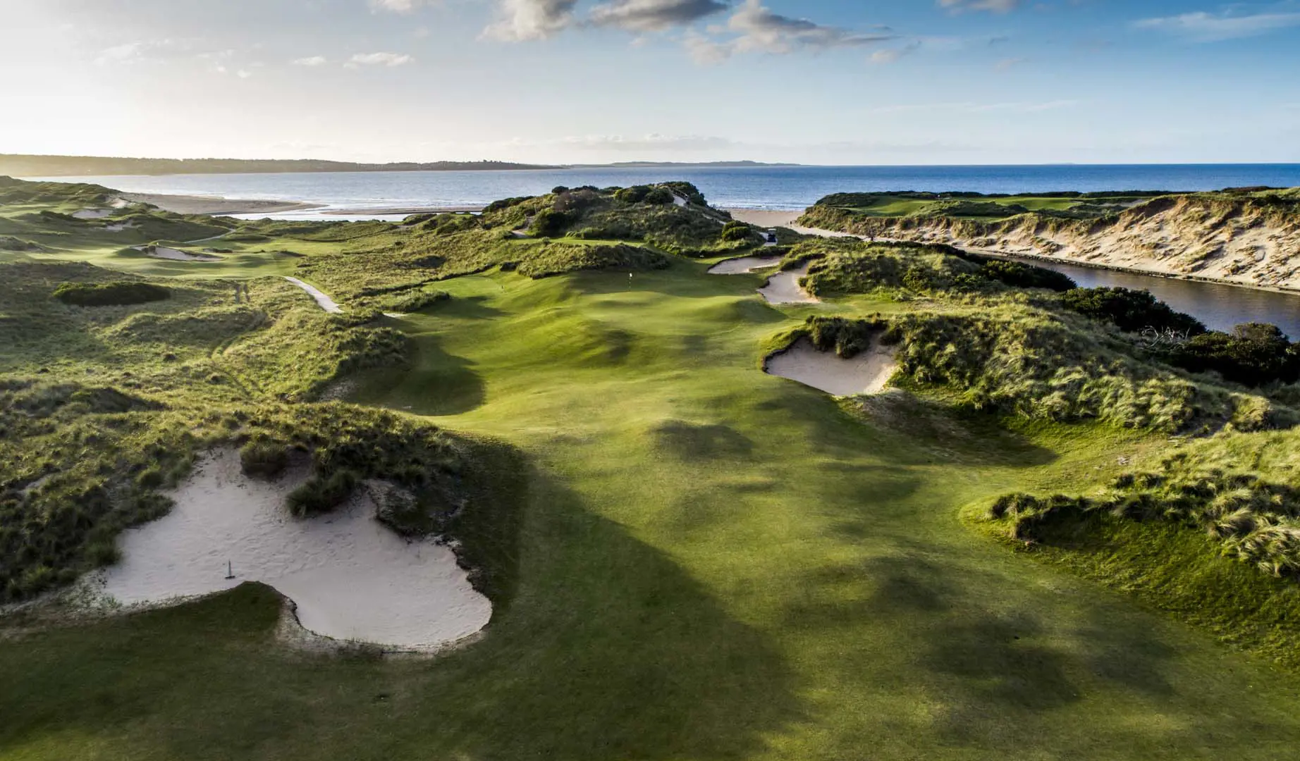 Wide green landscape at Barnbougle Dunes Golf Links, with the ocean in the backdrop.