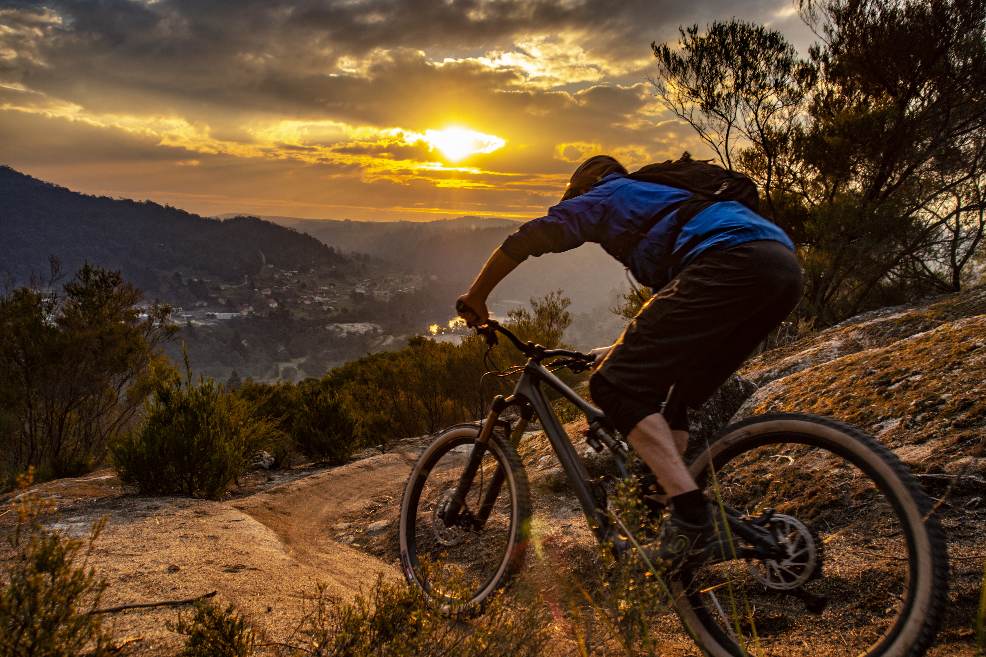 A cyclist on the Blue Derby Mountain Bike Trail in the foreground, with views of the town in the background.