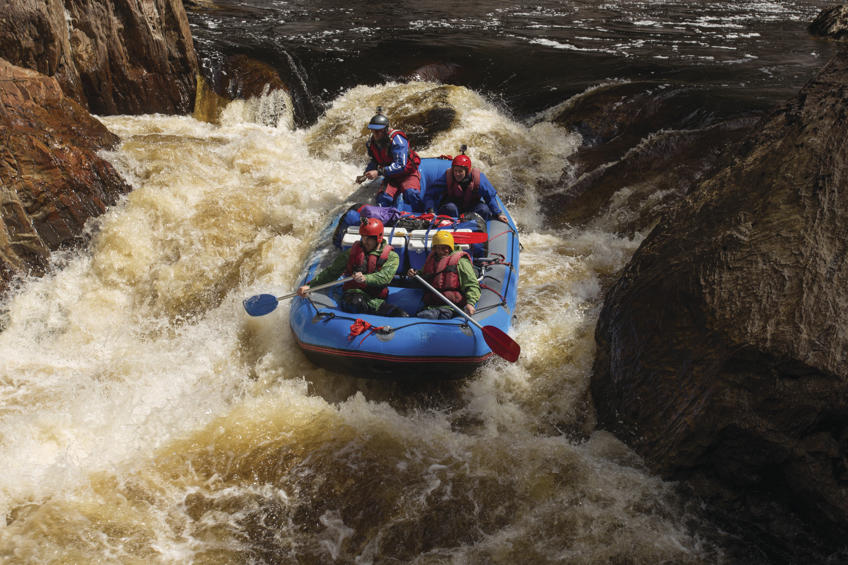 Intense image of four people white water rafting in rough waters on the Franklin River.