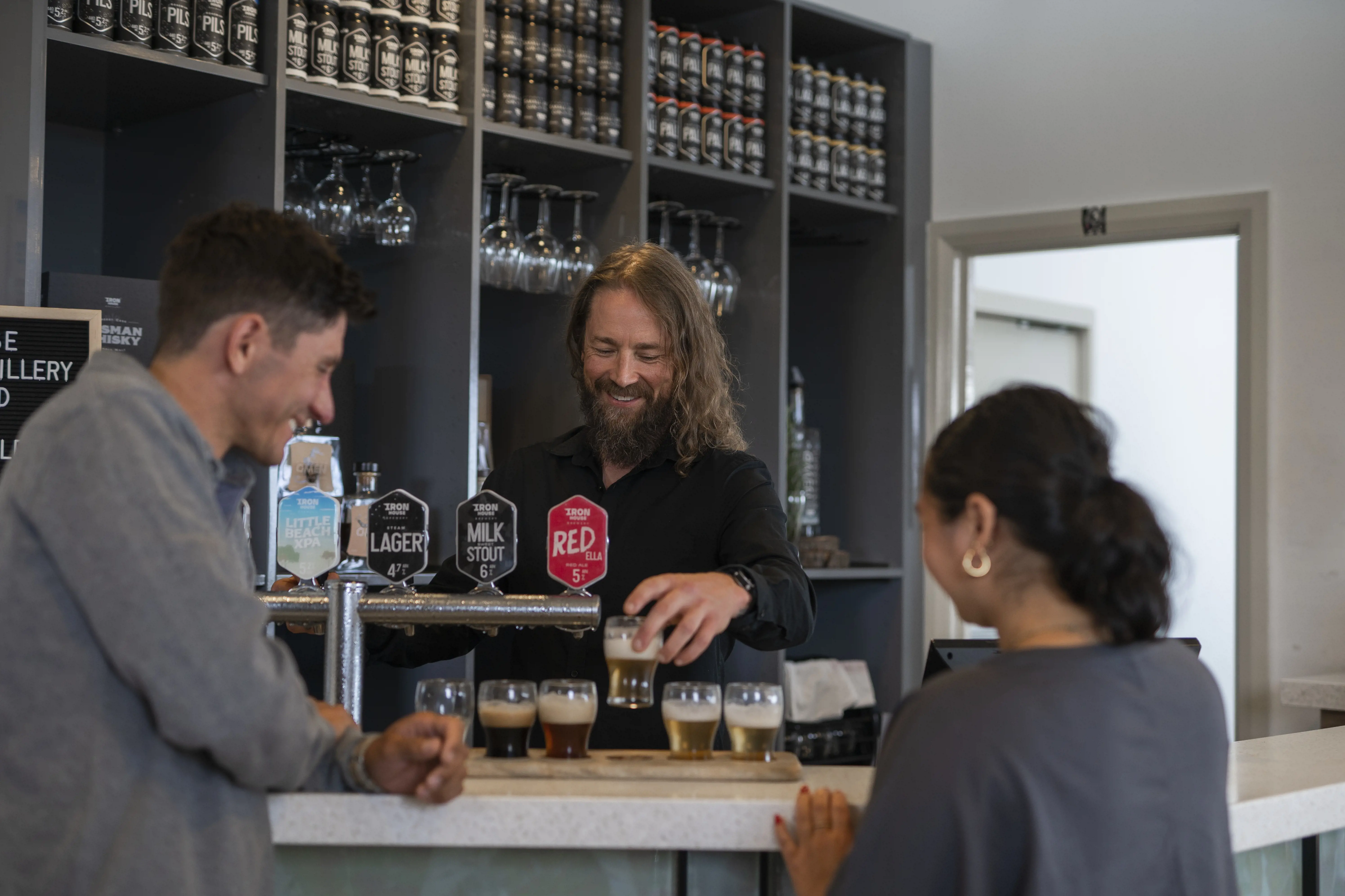 A couple stand at the Ironhouse bar and sample from a selection of beers.