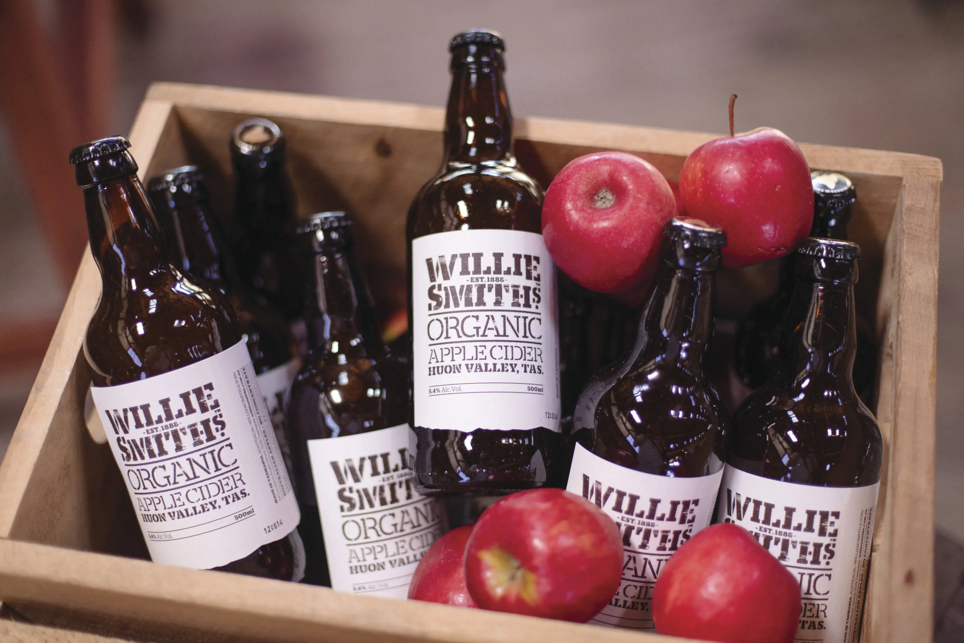 Close up image of bottles of cider and apples in a crate.