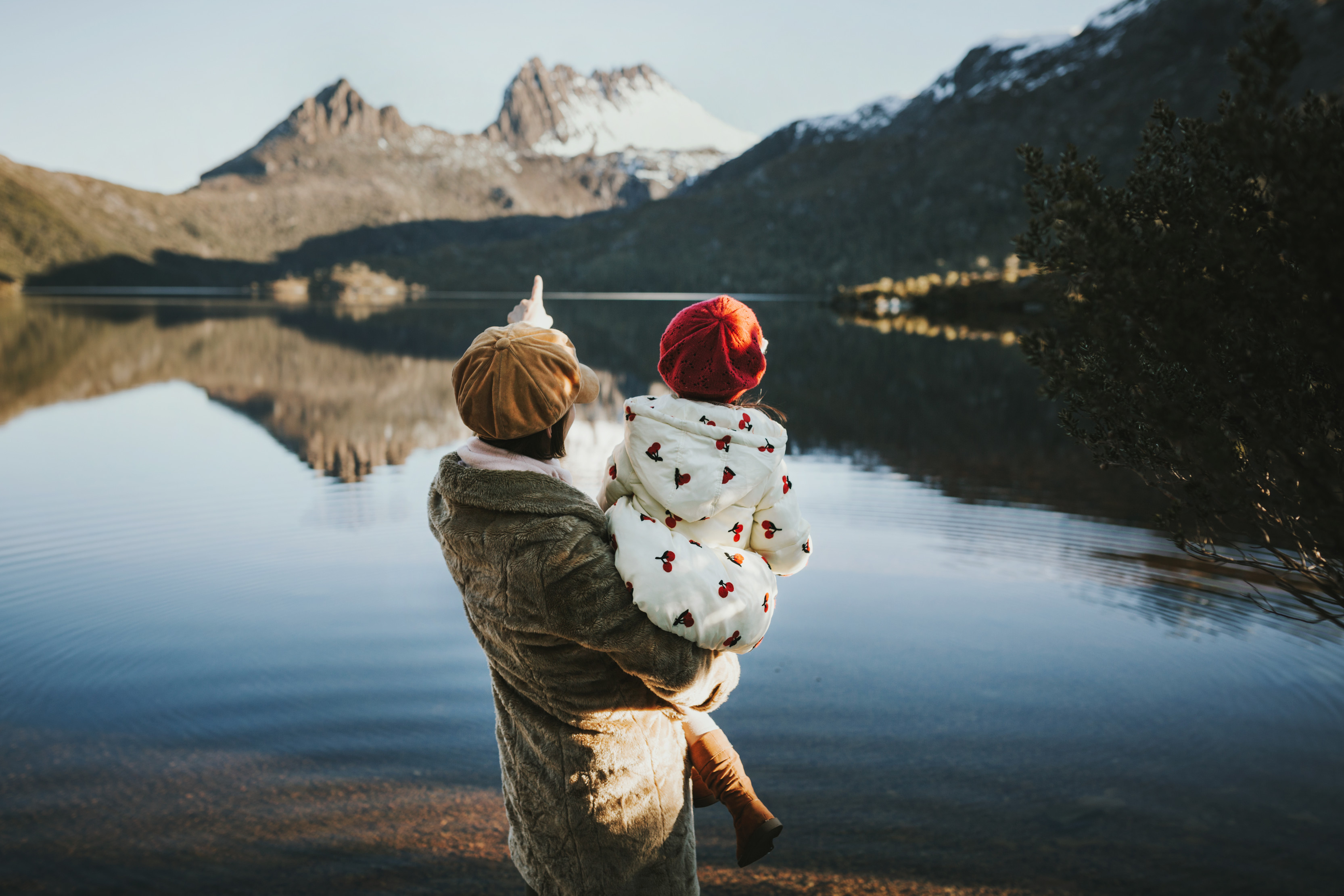 Daughter in mother's arms looking out into the incredible scenery of Cradle Mountain and the lake that lies before it. 