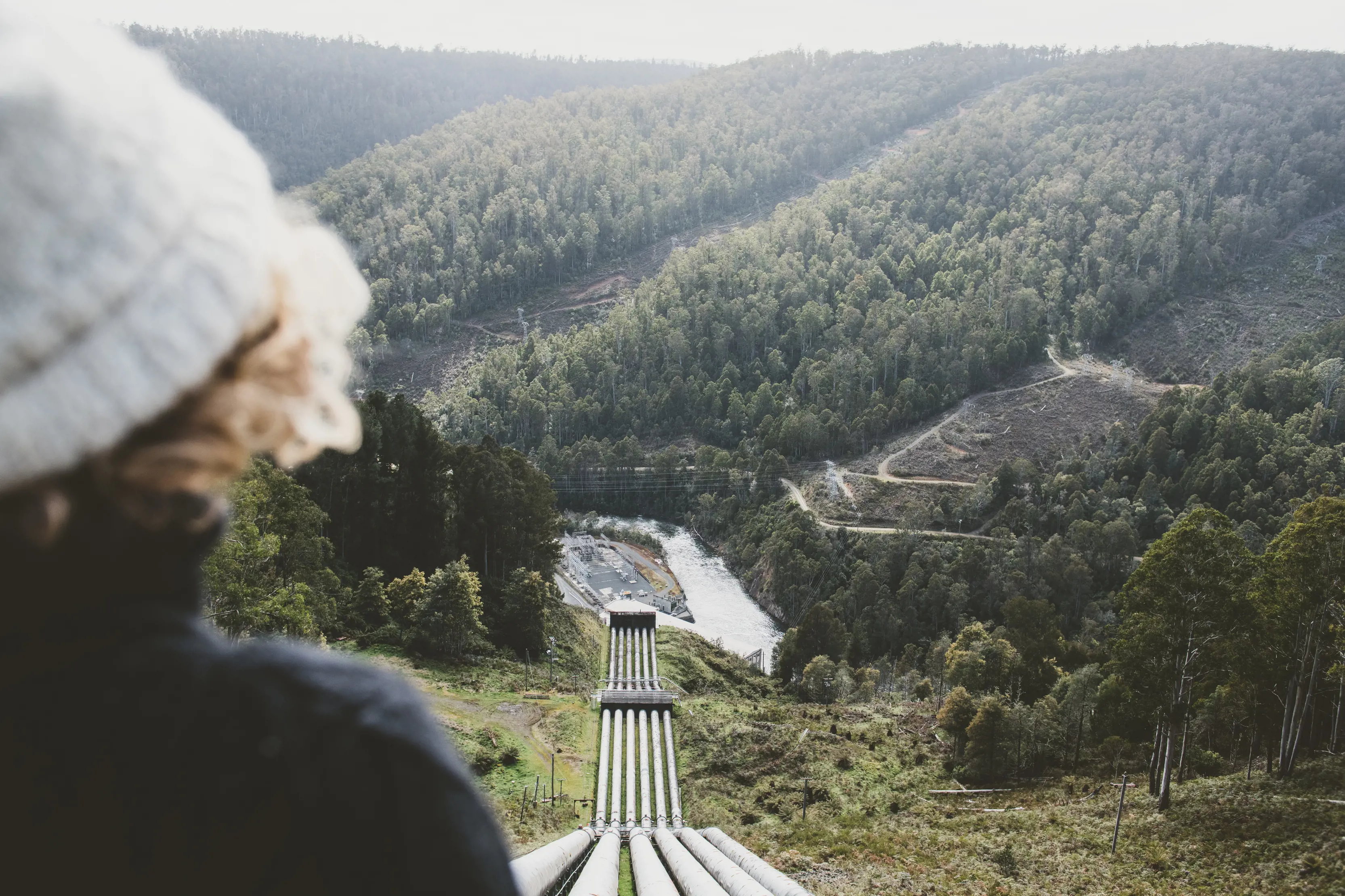 Image of a person in the foreground overlooking the penstocks feeding the Tarraleah Power Station, a hydroelectric power station located in the Central Highlands.
