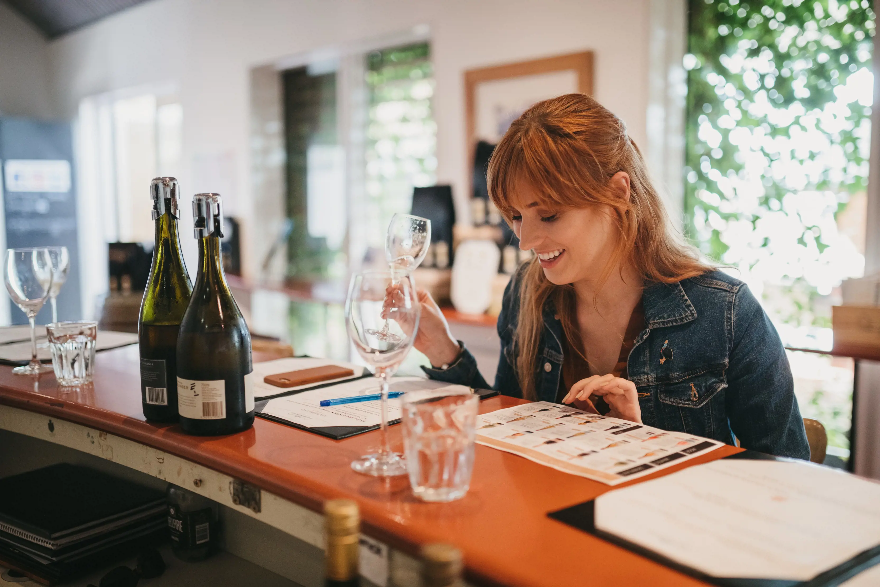 Lady holding empty glass, looking at the menu inside Pipers Brook Vineyard.