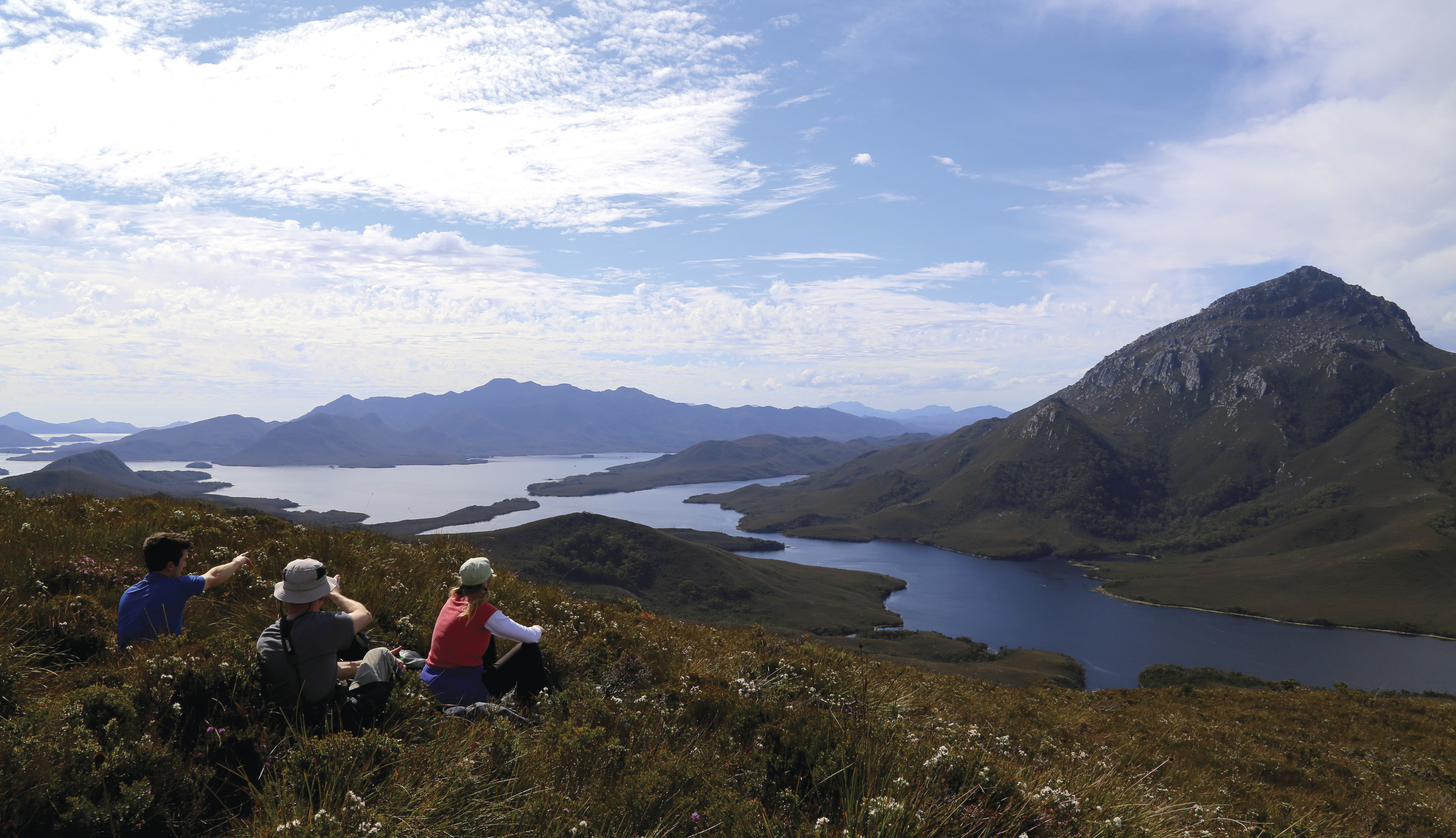 Three people taking a rest and exploring the incredibly remote waterways and wilderness of Bathurst Harbour/ Port Davey.