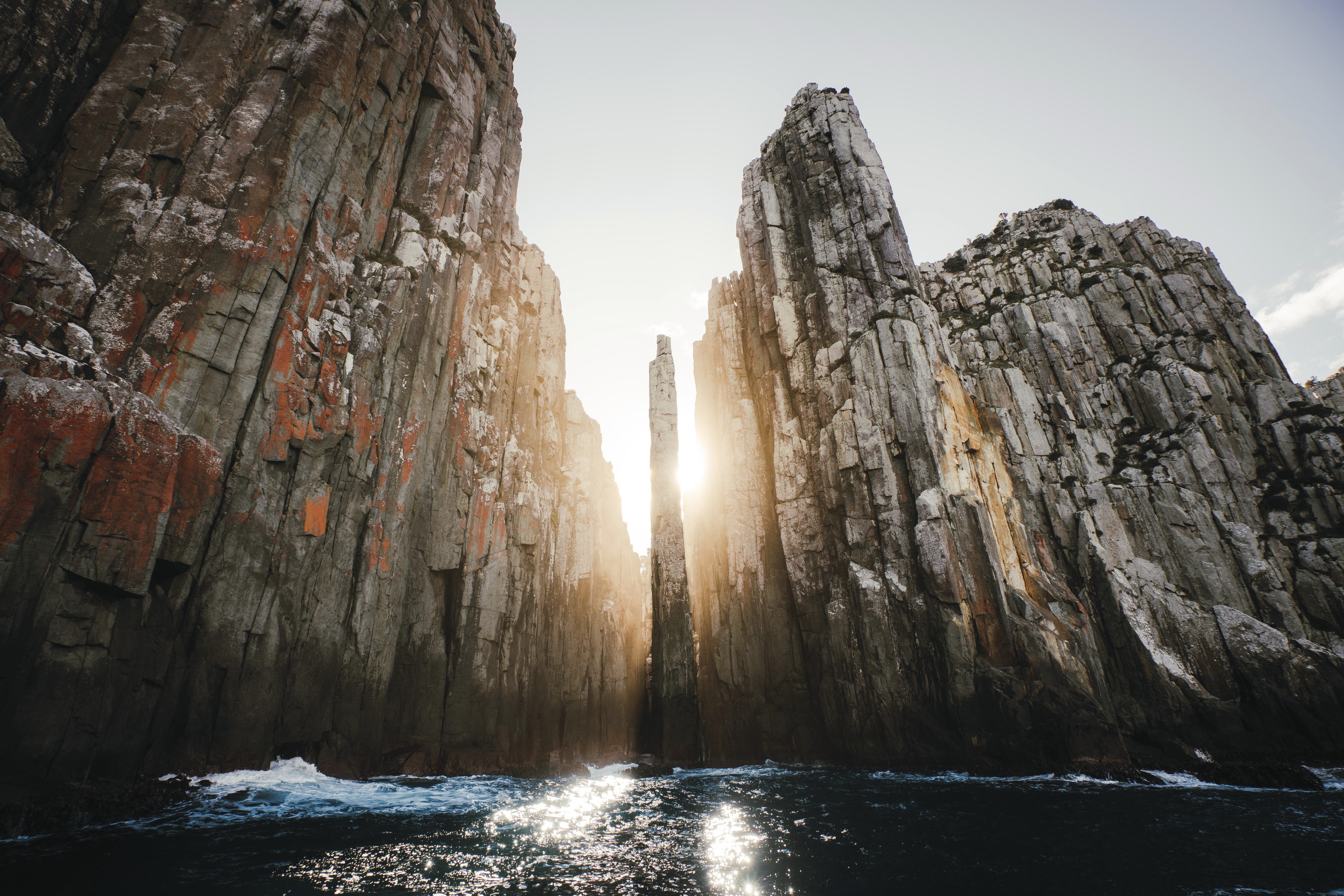 Breathtaking image of the Candlestick, taken from the ocean. Surrounded by tall rock walls and striking blue ocean as the sun peaks just the rocks.