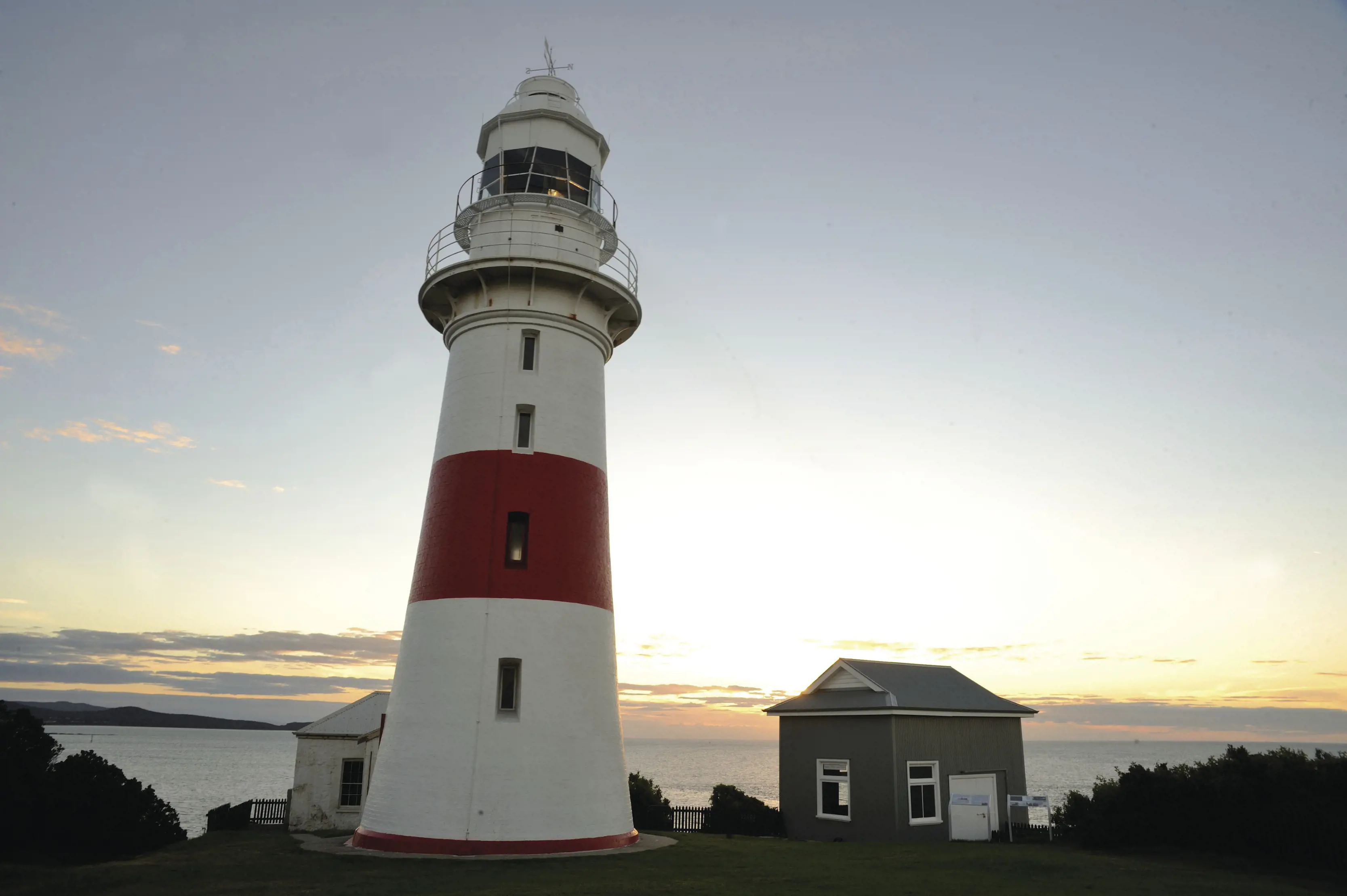 Close shot of Low Head Lighthouse, with a collection of cottages surrounding and beautiful water views.