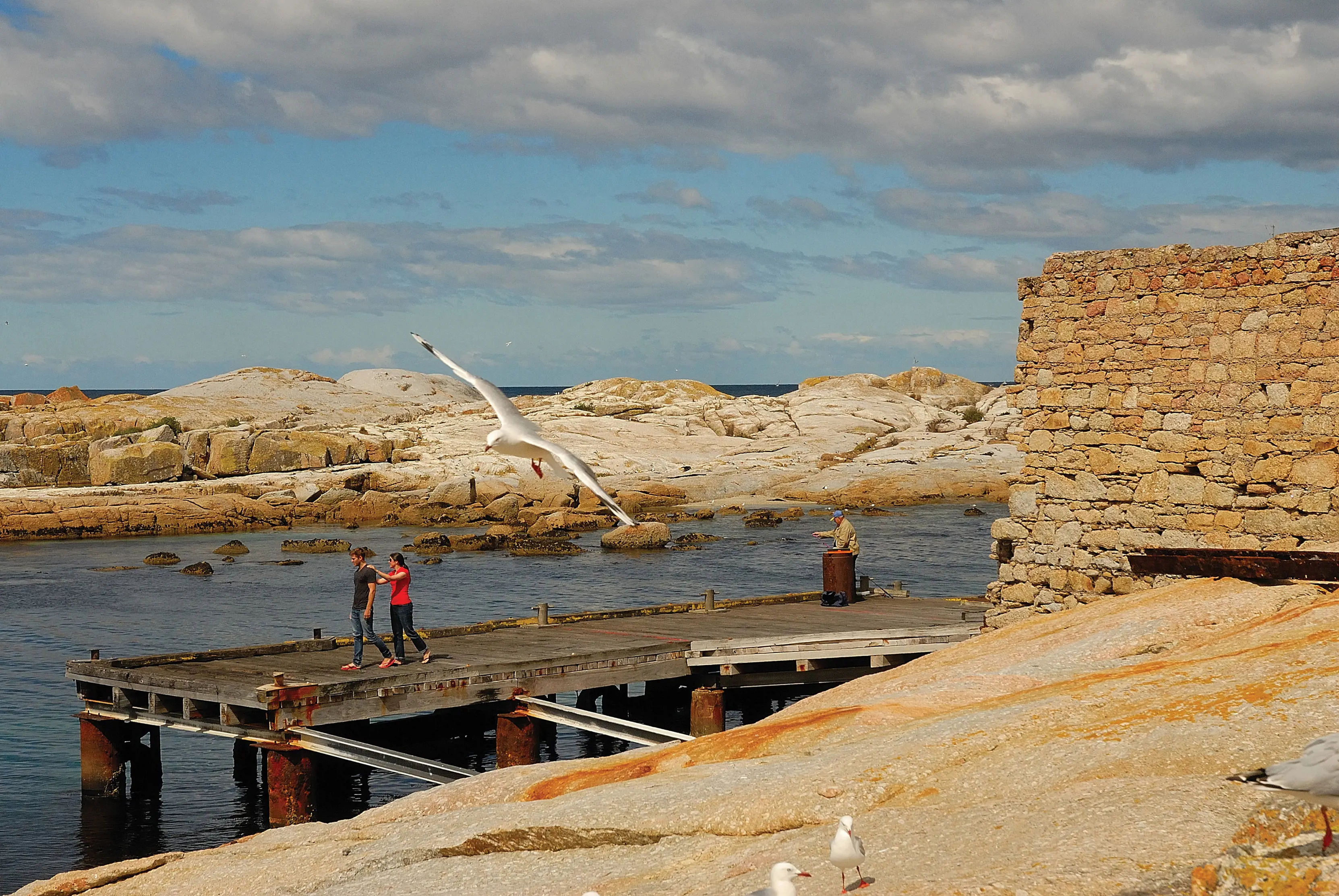 Two people walking along the jetty, sightseeing, at The Gulch, Bicheno.