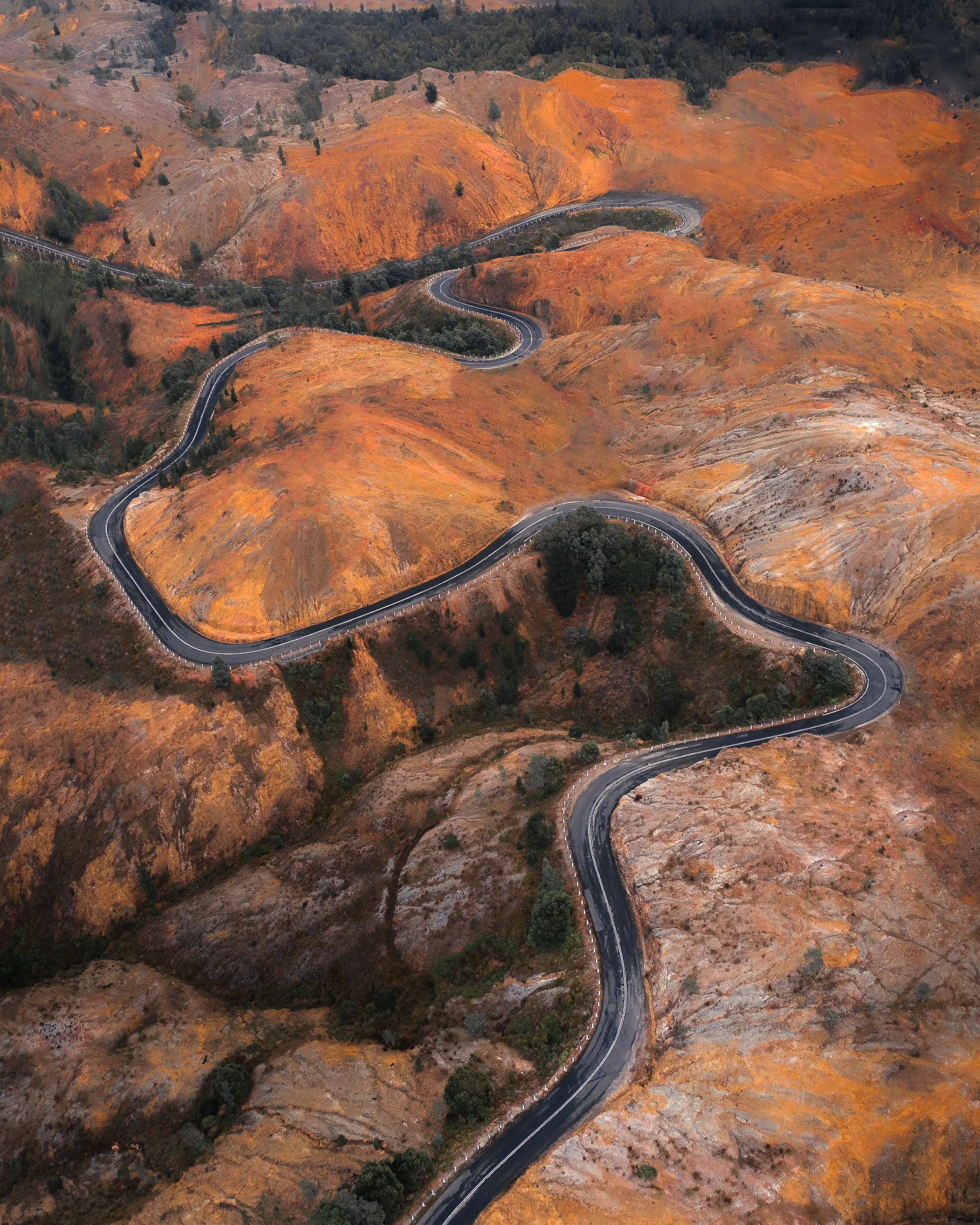 Aerial of Road into Queenstown, surrounded by a rocky 'moonscape' of bare coloured conglomerate, created by the copper mining and mass logging in the early 1900s.