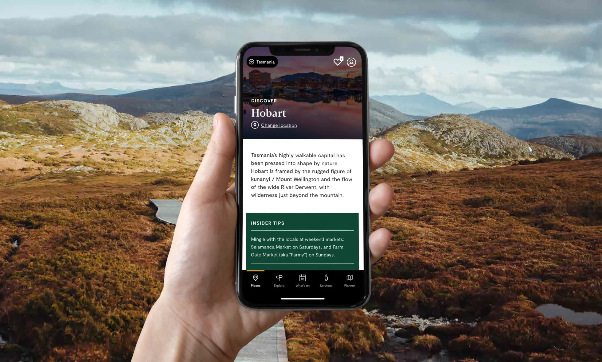 A hand holding a phone running the Discover Tasmania app